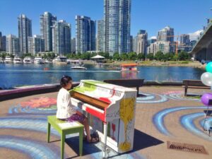 young girl playing piano by the water in Vancouver