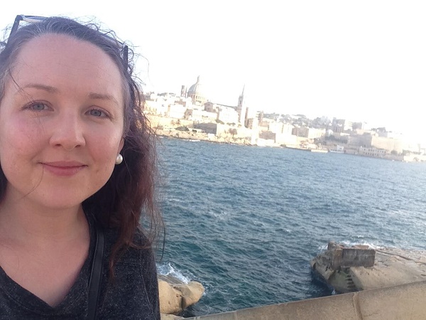Girl smiling in front of the skyline of Valletta, Malta